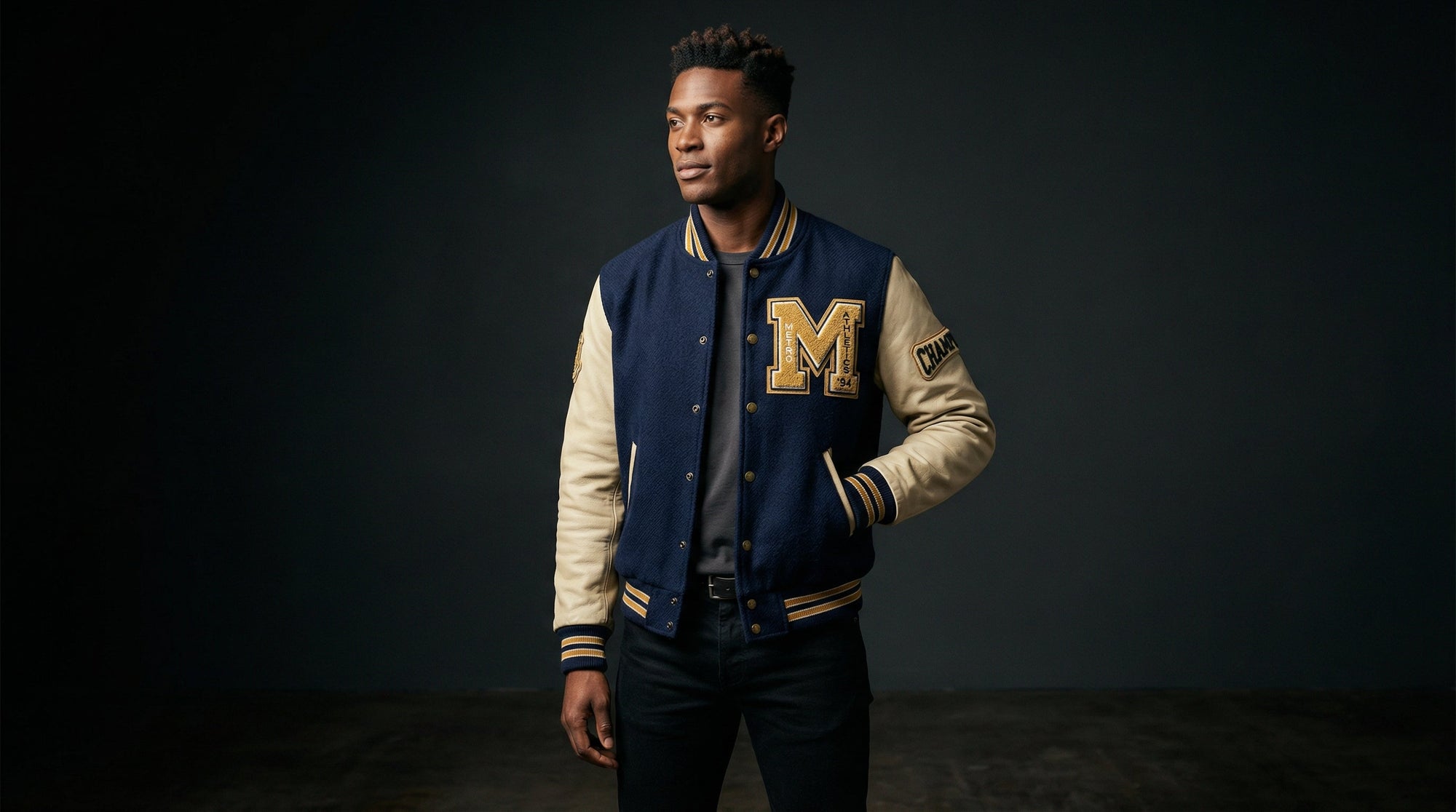 Man wearing a blue and cream varsity jacket in a studio for a what is a varsity jacket style guide